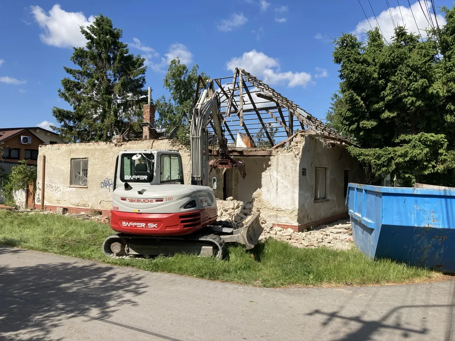 Bager Takeuchi pri búraní domu s kontajnerom na stavebnú suť